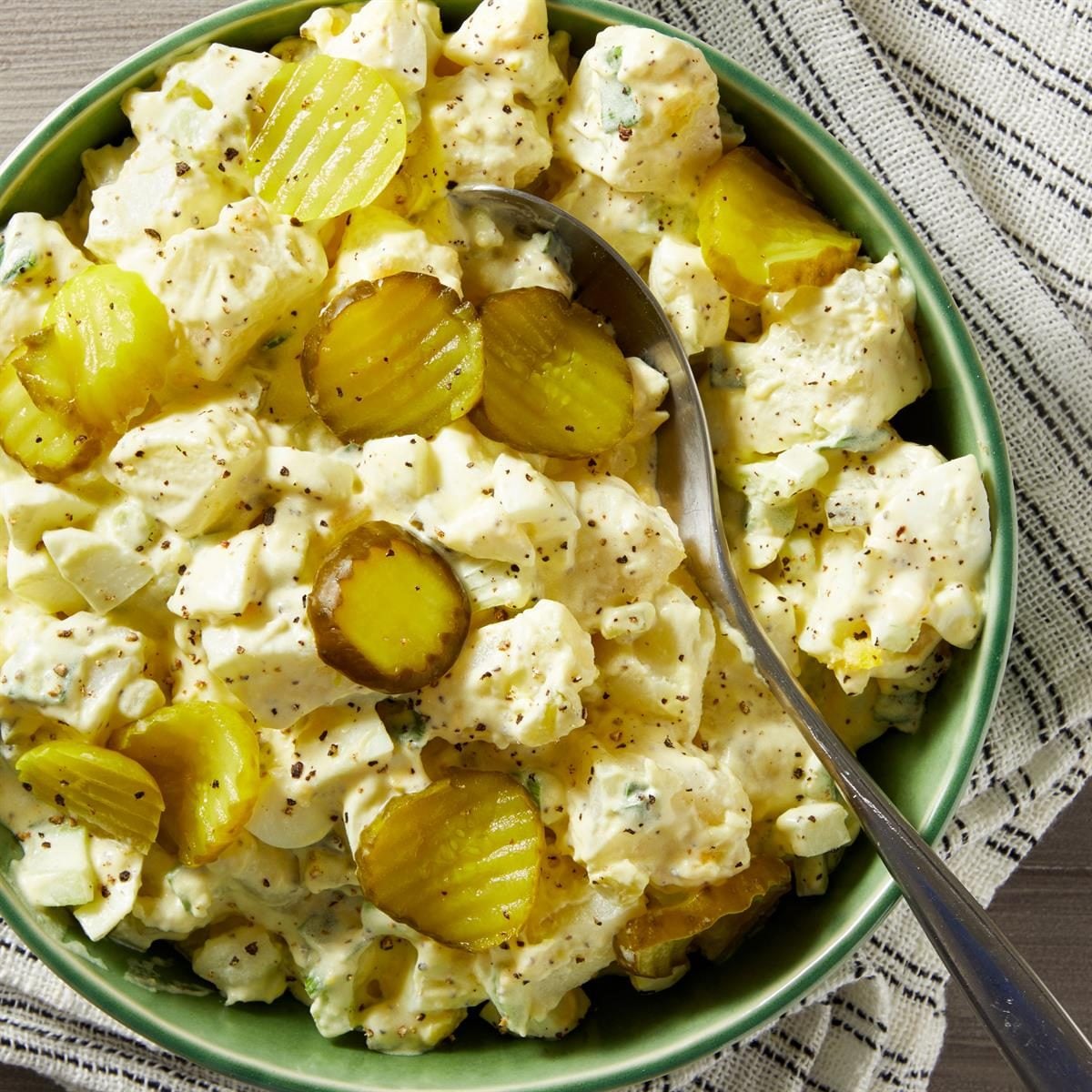 dill pickle potato salad in a bowl with fresh herbs
