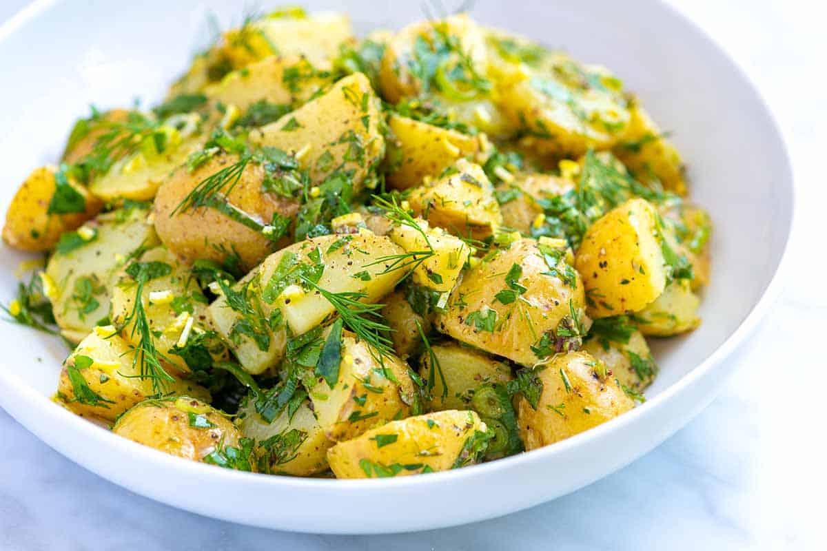 Lemon herb potato salad with fresh herbs in a picnic bowl