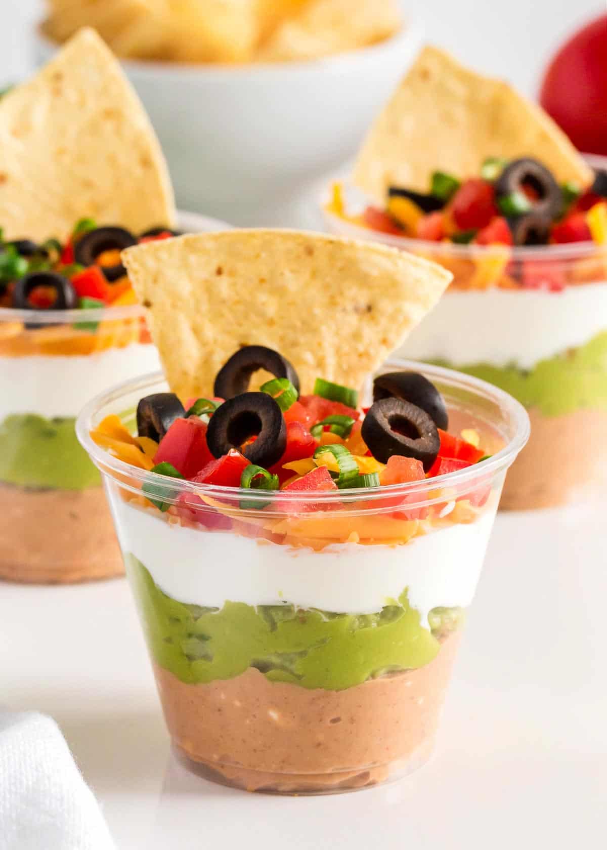 7 layer dip cups with refried beans guacamole sour cream and cheese
