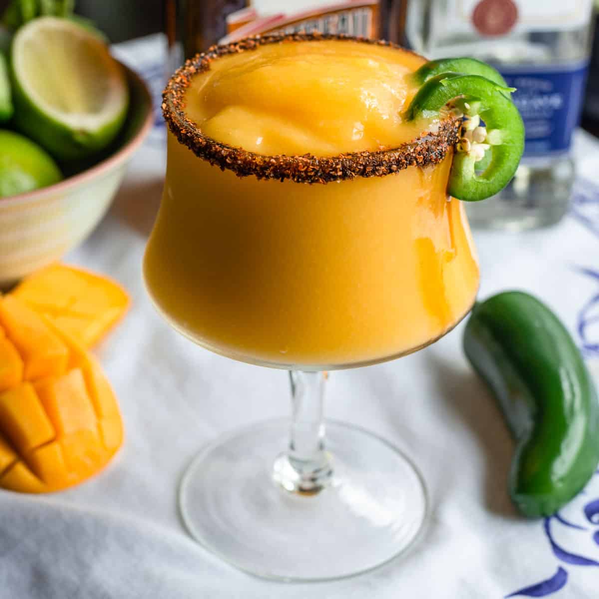 Mango jalapeno margarita in a glass with Tajin rim and mango jalapeño garnish