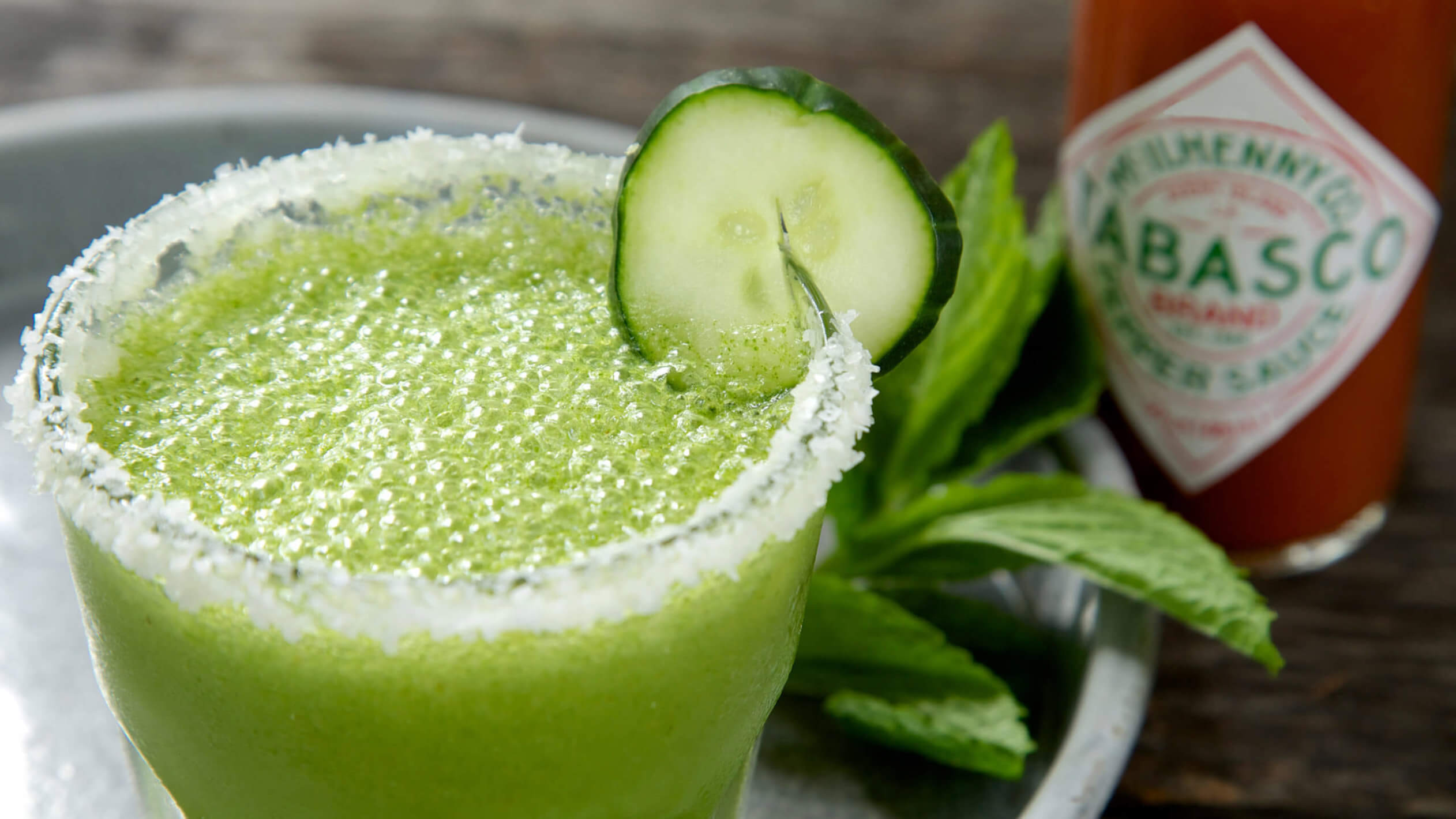 Cucumber mint margarita pale green with cucumber slice garnish