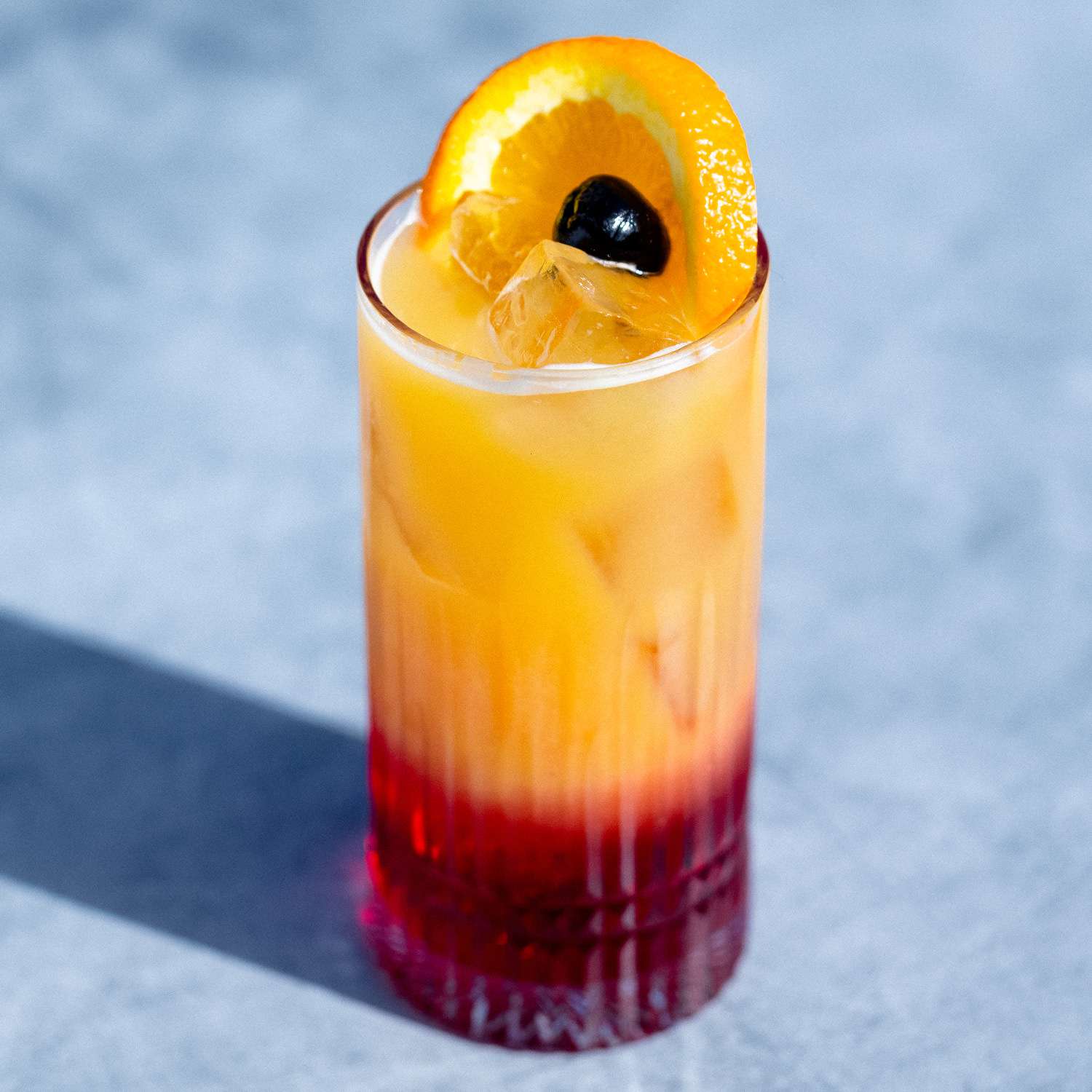 Tequila sunrise cocktail with orange to red gradient garnished with orange slice