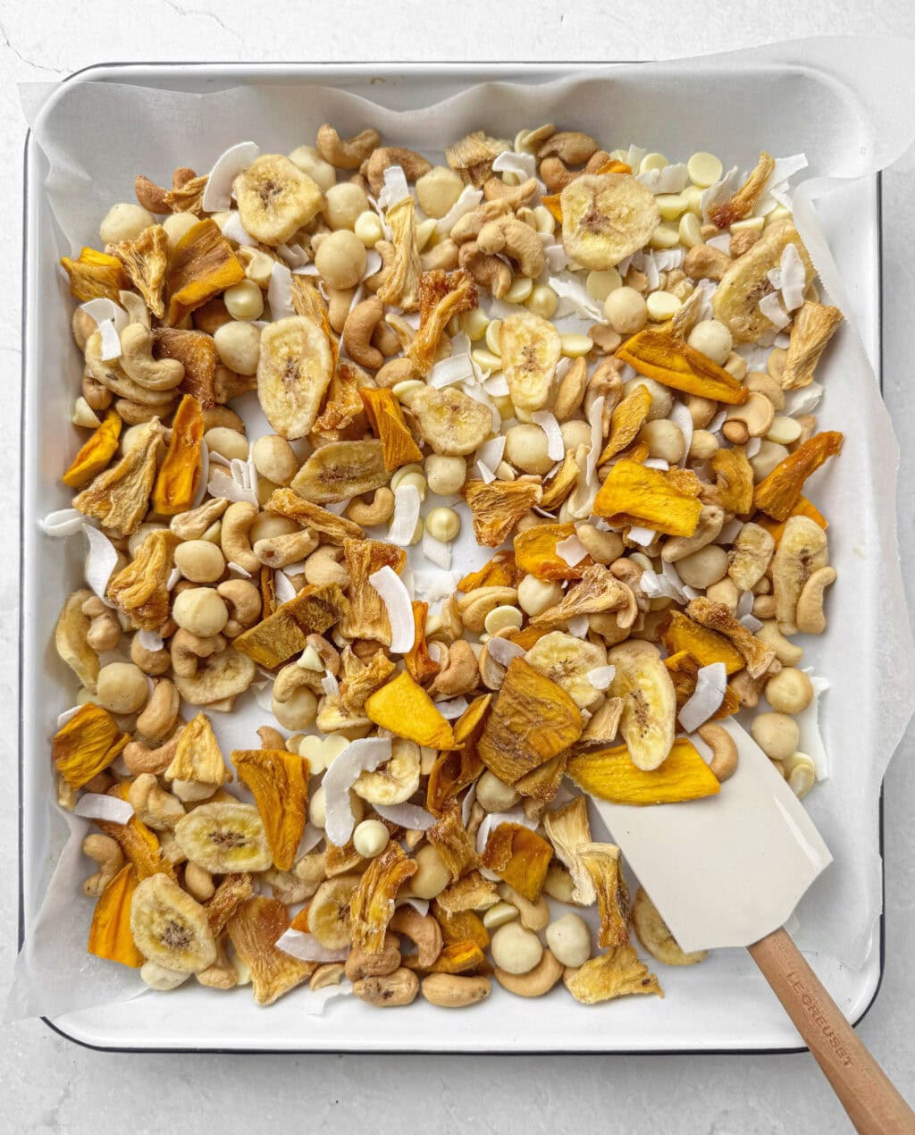 Tropical coconut trail mix with dried mango pineapple banana chips cashews and coconut flakes