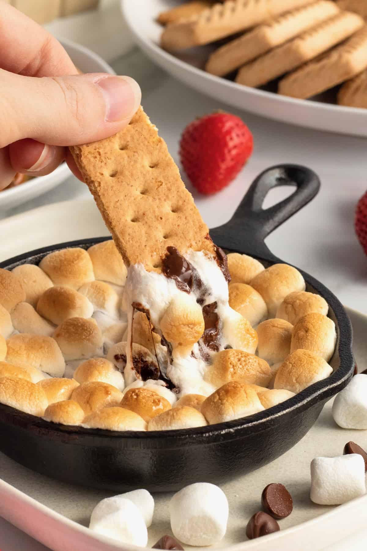 Skillet s'mores dip with melted chocolate toasted marshmallows and graham crackers