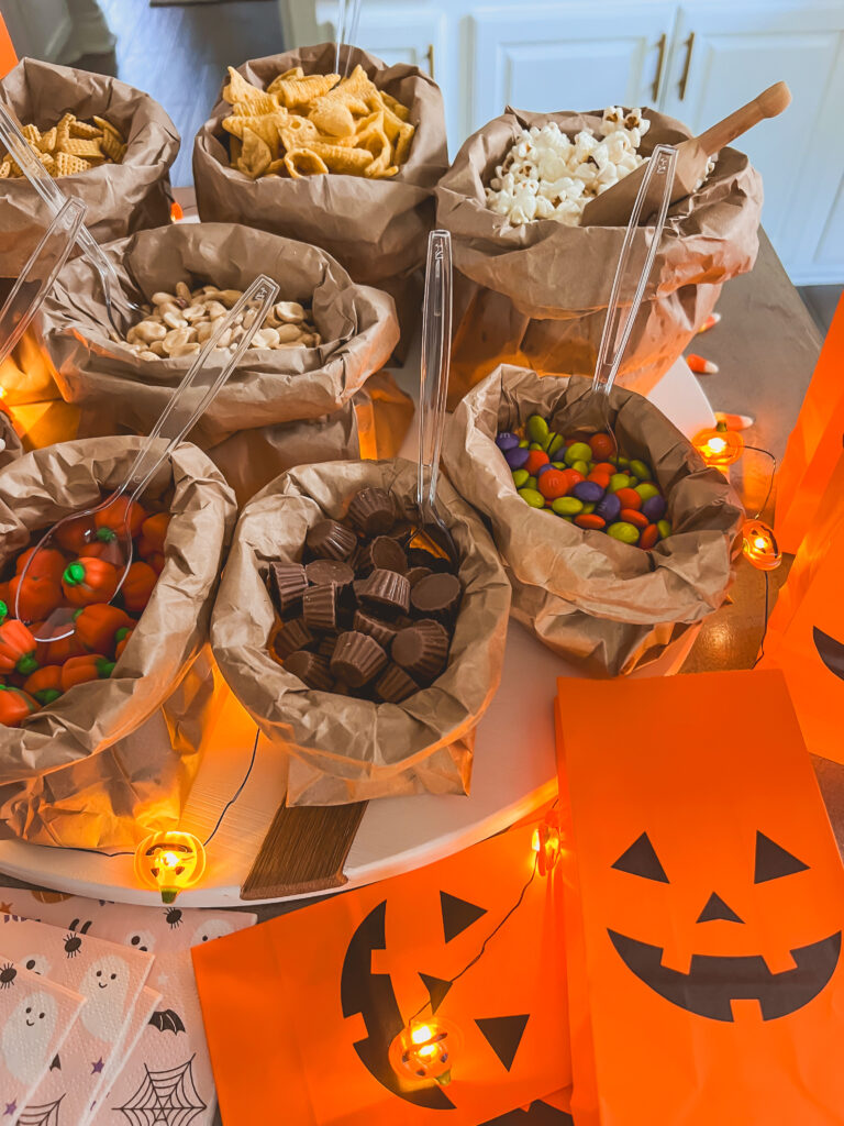 DIY trail mix bar board with nuts pretzels dried fruit chocolate candies popcorn and snack cups
